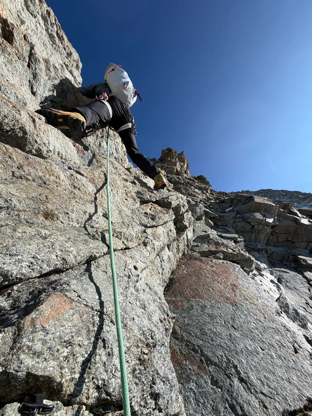 Une cordée grimpe sur une arête rocheuse, avec la corde au premier plan