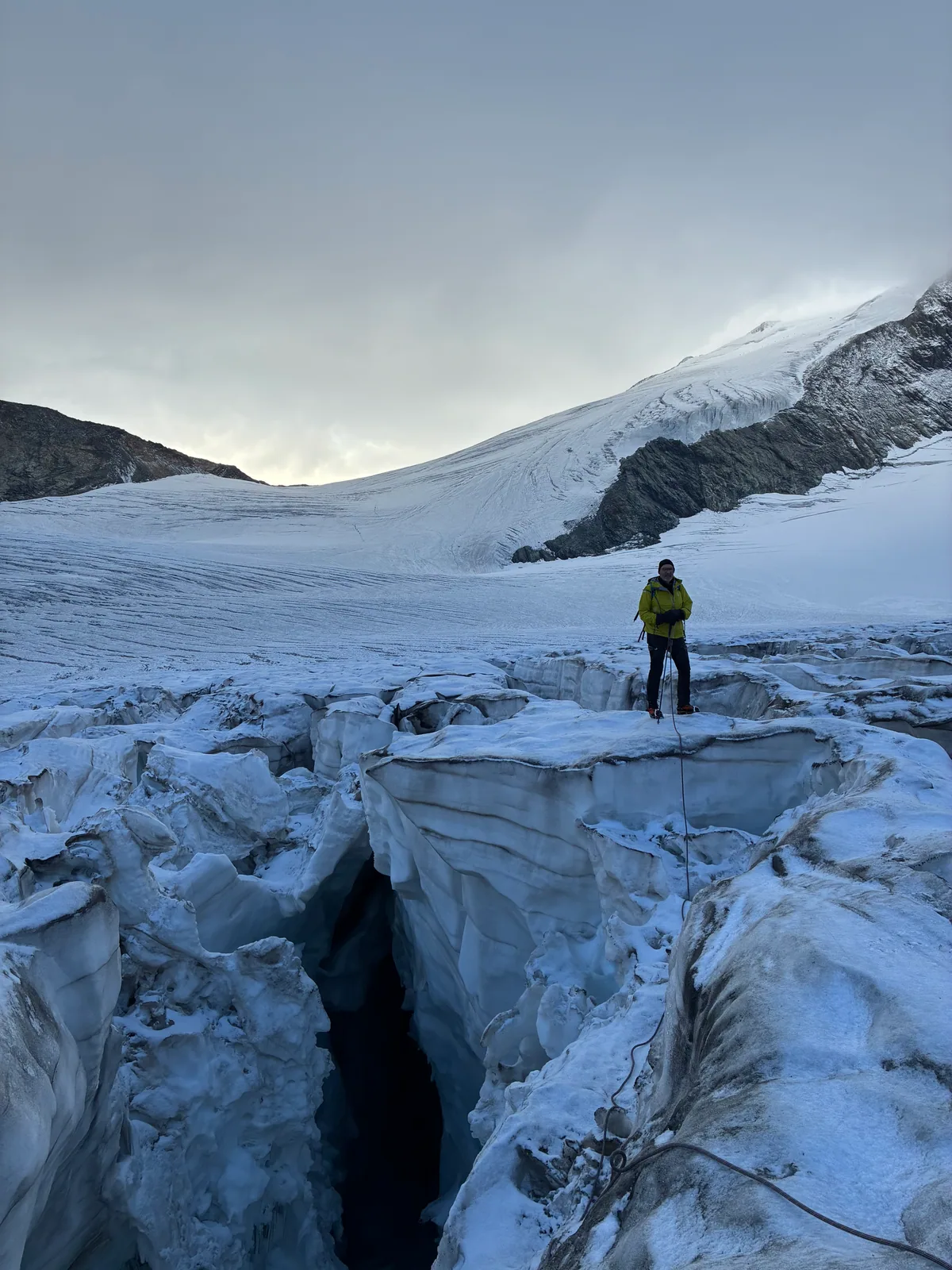 Une personne encordée se tient sur un glacier au-dessus d’une crevasse