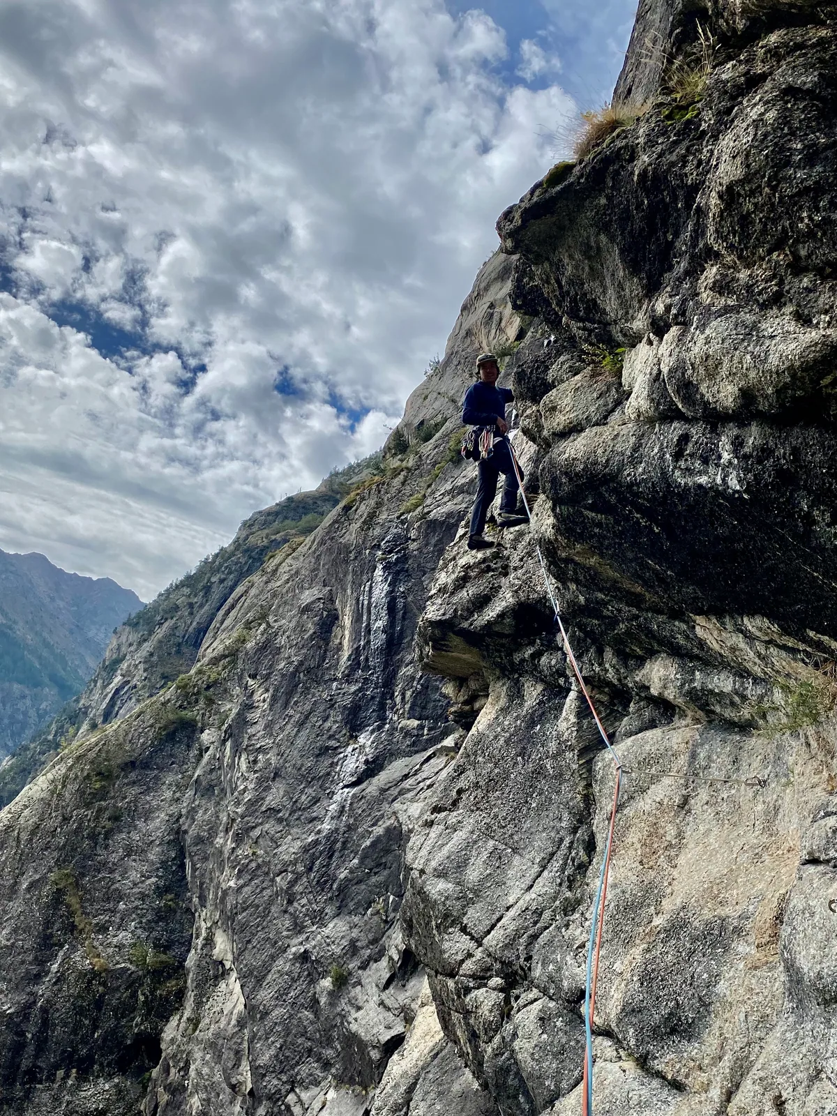 Une cordée progresse sur une arête rocheuse sous un ciel nuageux