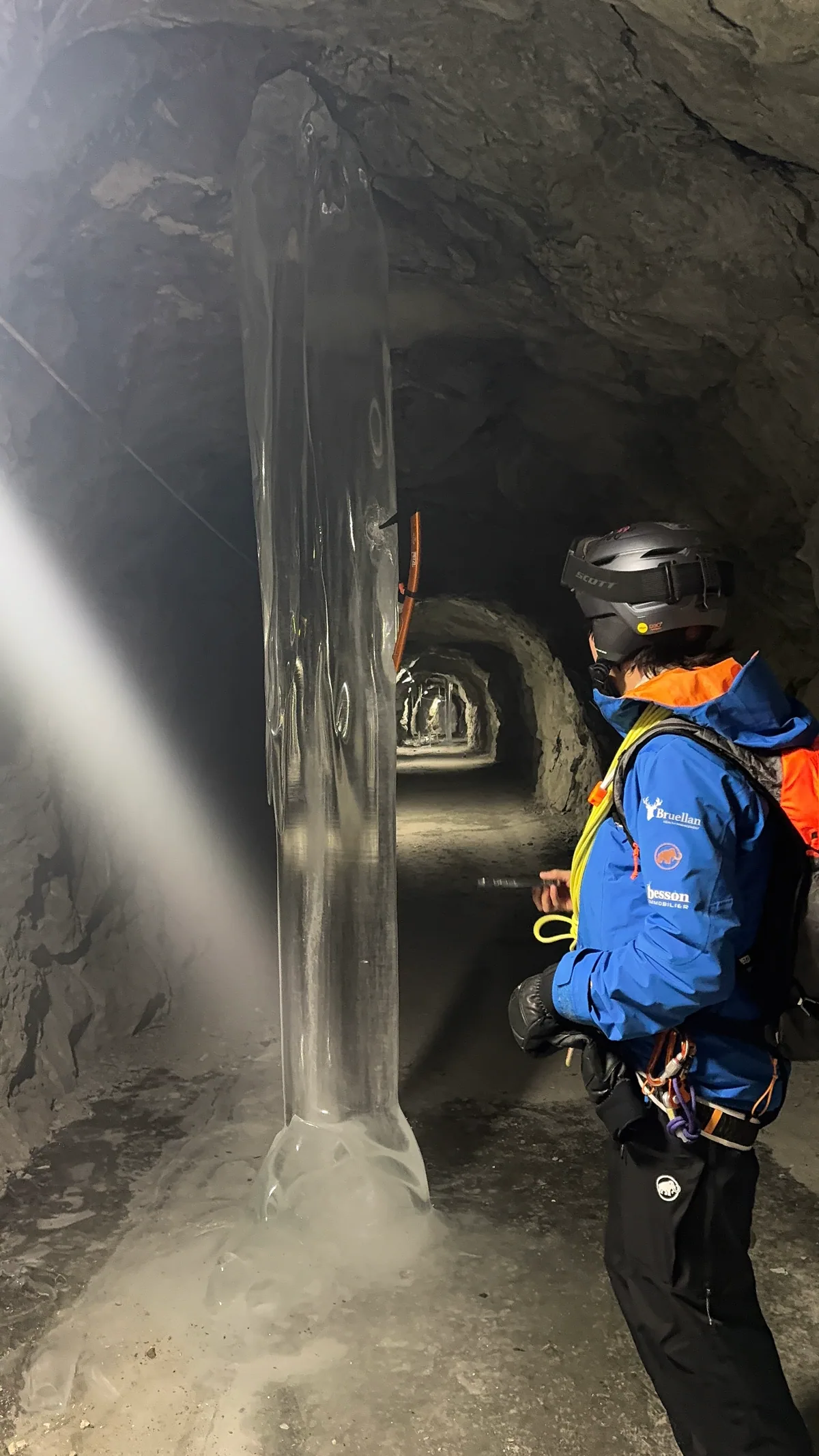 Un participant casqué observe une cascade au cœur du canyon