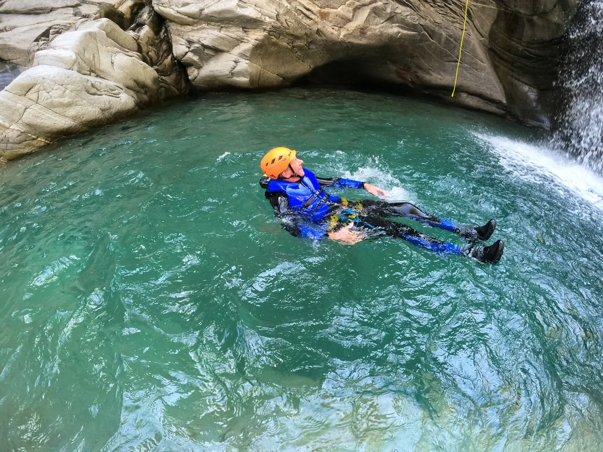 Un participant en combinaison et casque flotte dans une vasque turquoise