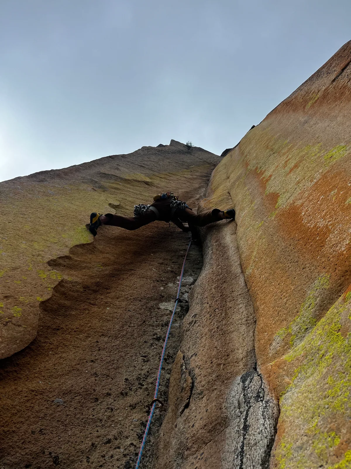 Un grimpeur dans une fissure rocheuse au-dessus des alpages