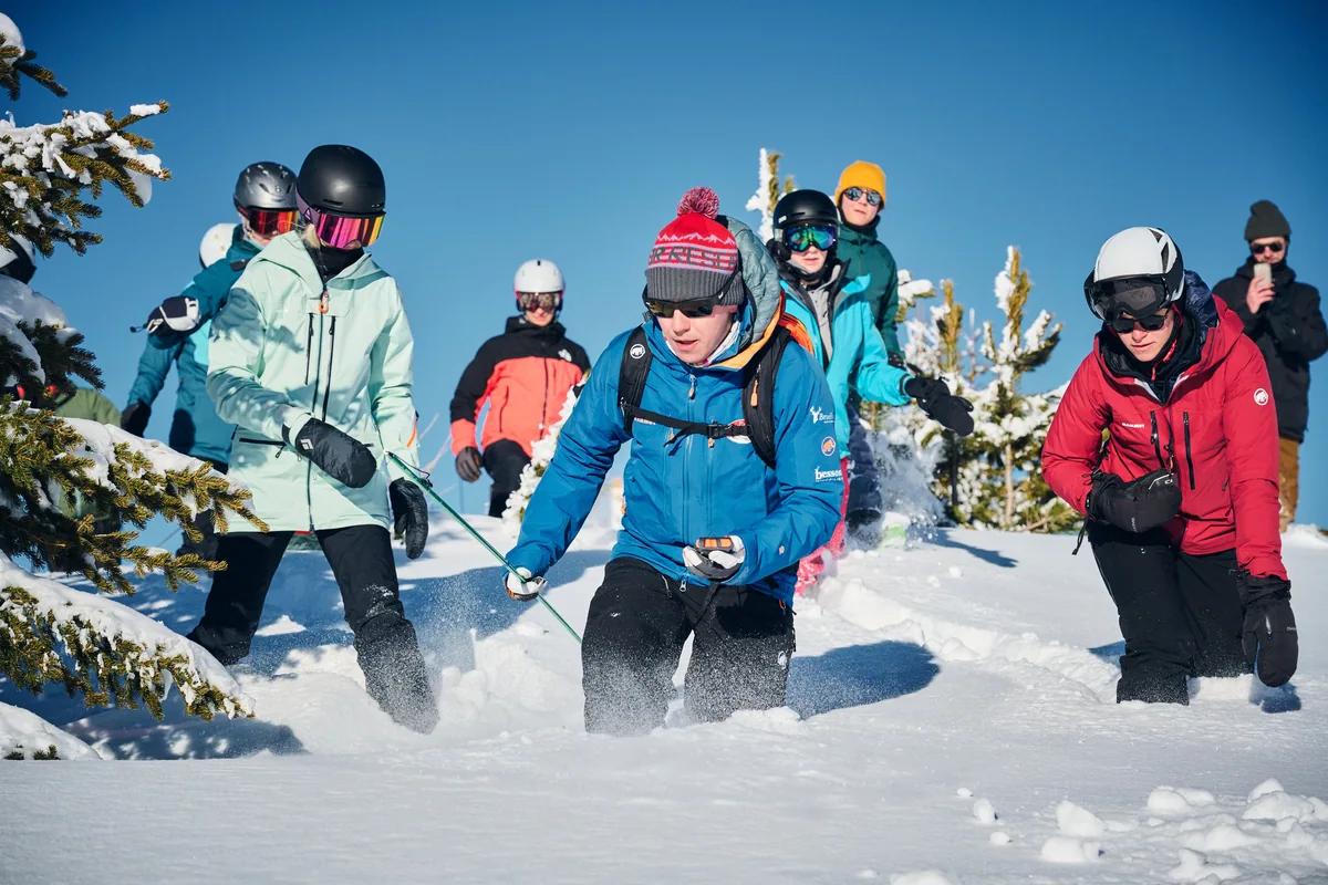 Josh montre la recherche avec un DVA à un groupe dans la neige