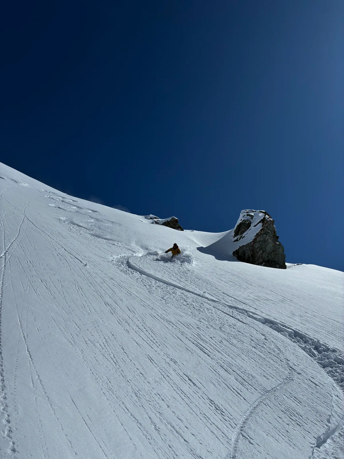 Une trace de ski dessine une pente enneigée entre les rochers