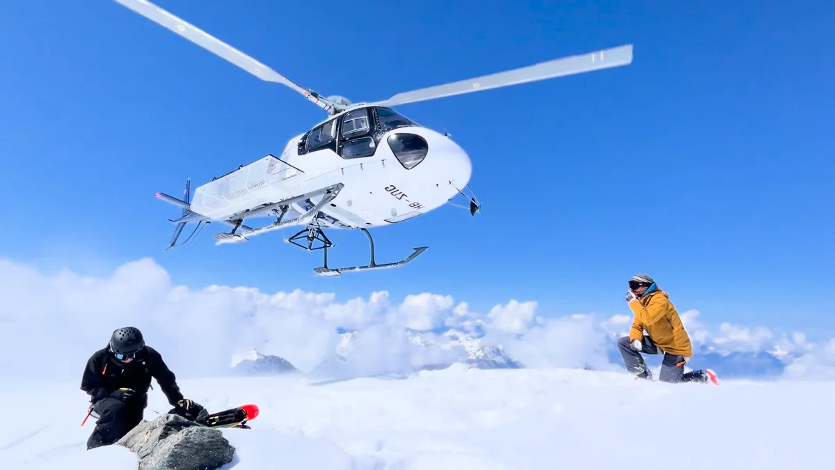 Un hélicoptère au-dessus de la neige, près de deux skieurs en montagne